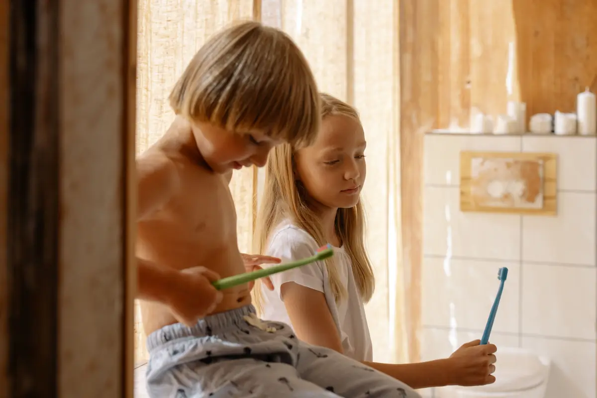 Two children brushing their teeth together at a bathroom sink